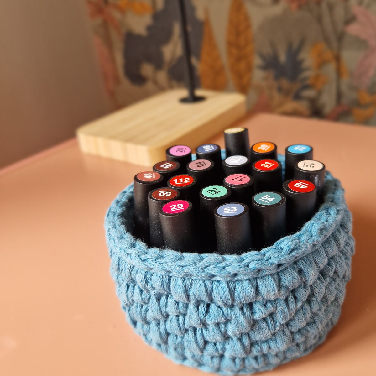 Blue handmade crochet trinket basket used to organise lipsticks
