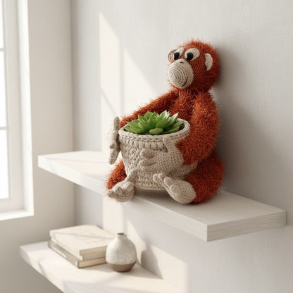 A textured crocheted orangutan holding a small crocheted plant pot cover containing a  succulent, displayed on a white floating shelf in a bright, minimalist room.