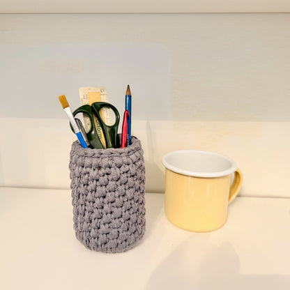 Handmade crochet storage pot show beside a standard mug to demonstrate size.