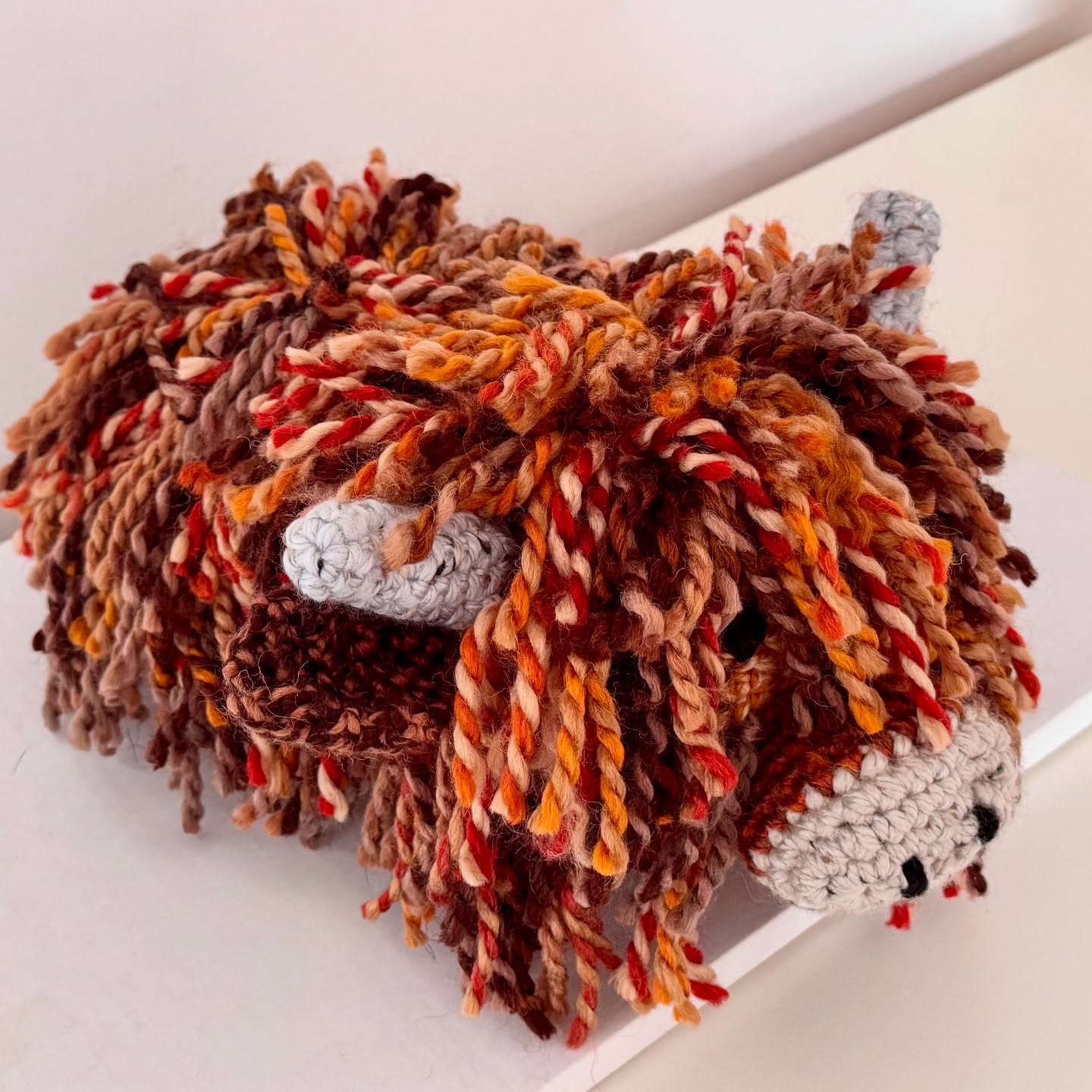 Side view of a handmade Highland Cow doorstop showing its wool texture and handcrafted detail.